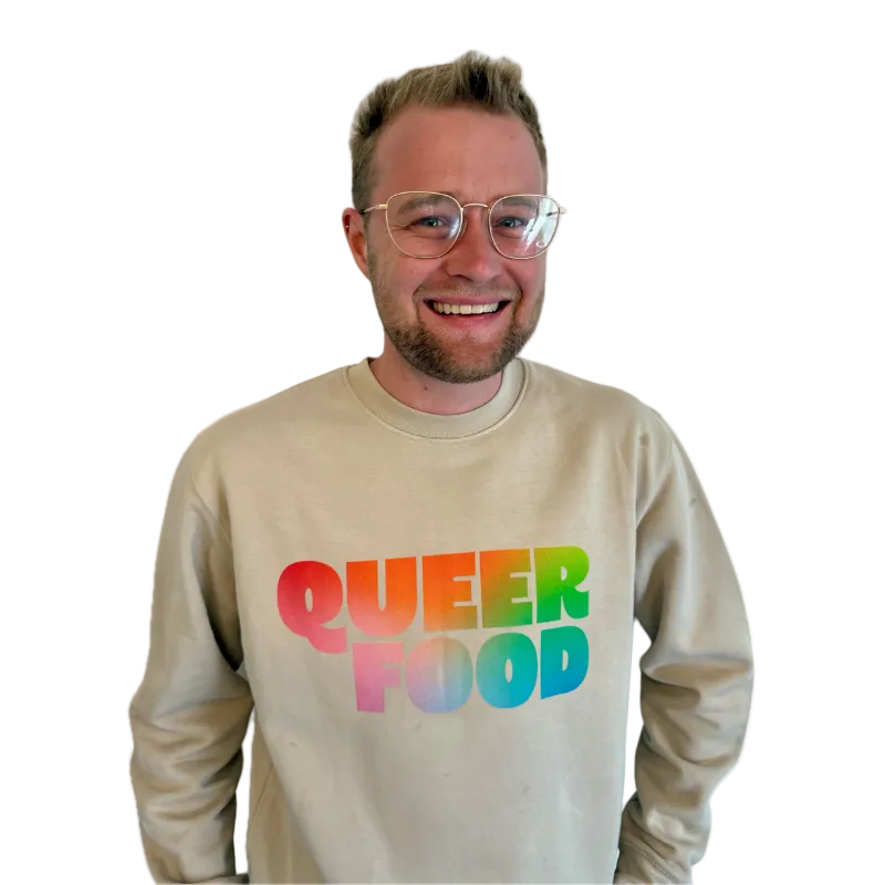Man wearing a beige sweatshirt with 'QUEER FOOD' in rainbow letters on a white background